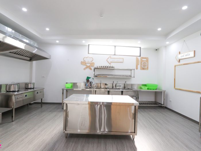 Bếp ăn của trường với bàn và bếp inox, bố trí theo quy trình một chiều