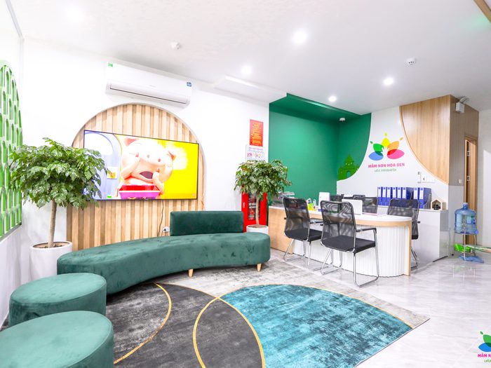 Sảnh đón của trường với ghế sofa xanh và quầy lễ tân có logo bông sen