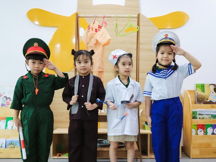 Bốn bé mặc trang phục các nghề trong buổi hoạt động hướng nghiệp của trường